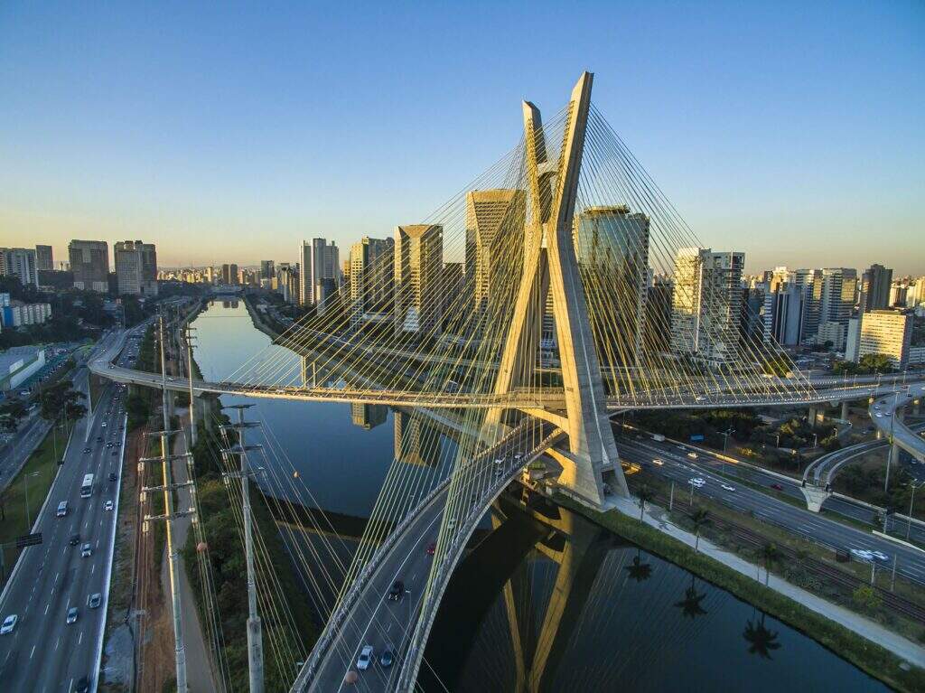 L'image présente une photo aérienne de la ville de São Paulo, centrée sur le pont de la rivière Tietê. 