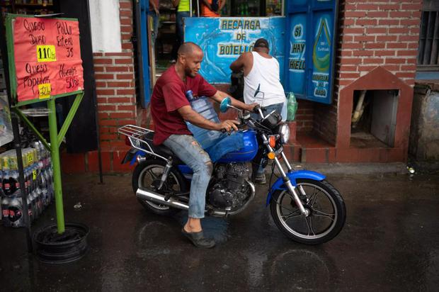 Un homme transporte de l'eau sur sa moto dans le quartier de La Vega à Caracas (Photo : AFP)