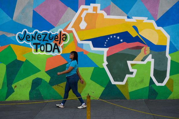 Un piéton passe devant une fresque murale sur laquelle on peut lire « Tout le Venezuela », lors d