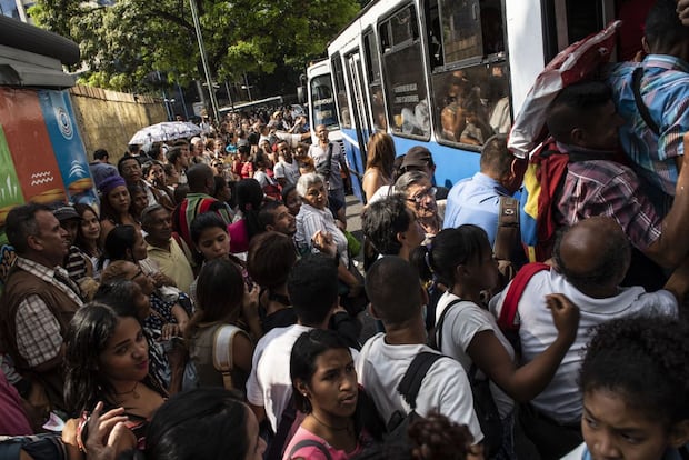 Les passagers tentent de monter à bord d'un bus public lors d'une panne de courant à Caracas, en mars 2019. Source: Bloomberg