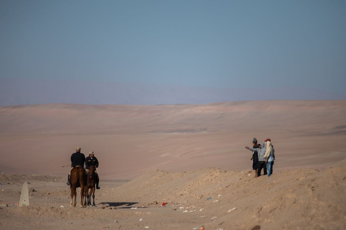 Des policiers parlent avec des migrants à la frontière entre le Pérou et le Chili, à Tacna, au Pérou.