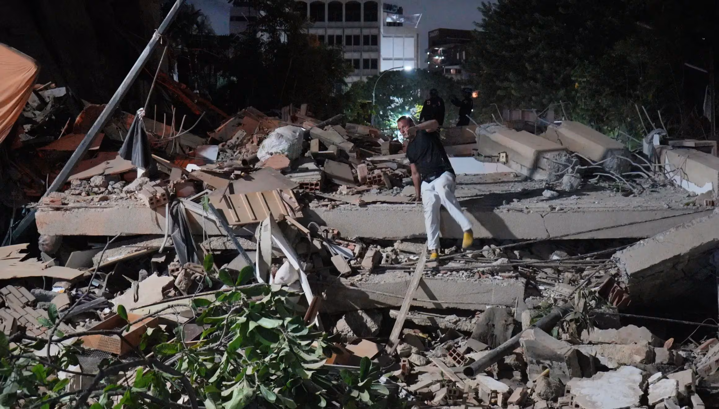 Un homme saute par-dessus un bâtiment effondré après un tremblement de terre à Caracas, au Venezuela, le mercredi 24 juin 2026. (AP Photo/Adrian Naranjo)