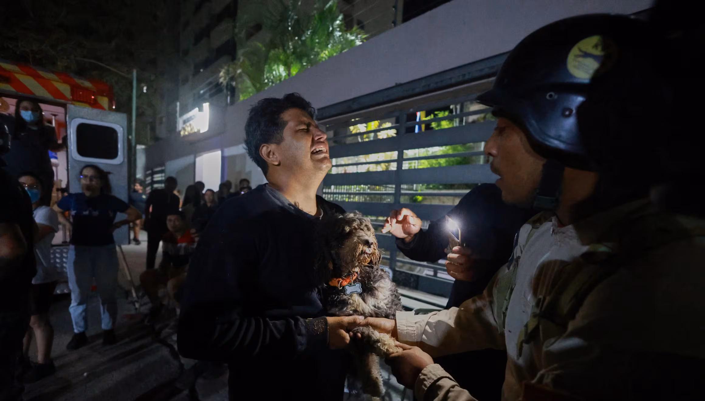 Un homme tenant un chien pleure après un tremblement de terre à Caracas, au Venezuela, le mercredi 24 juin 2026. (AP Photo/Javier Campos)
