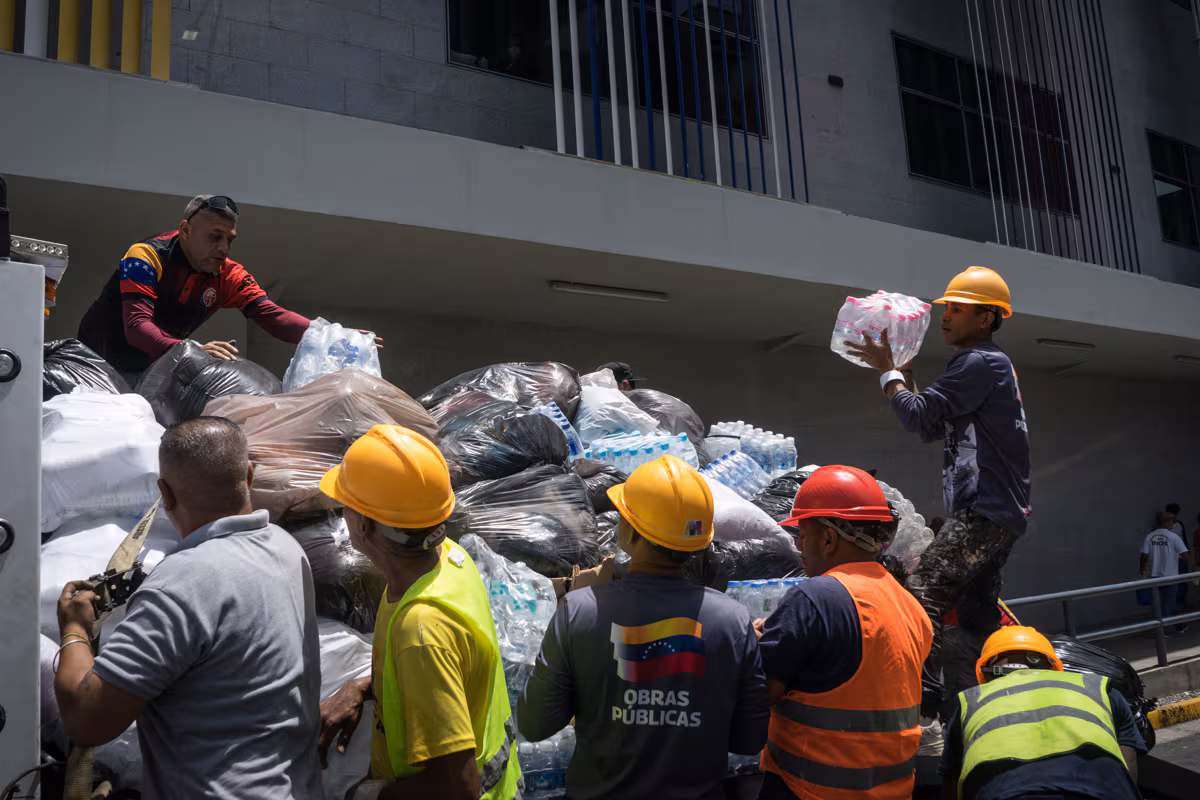 Des gens transportent des colis contenant des dons, à l'hôpital Domingo Luciani de Petare à Caracas, au Venezuela, le 26 juin 2026. (Boris Vergara / EFE)